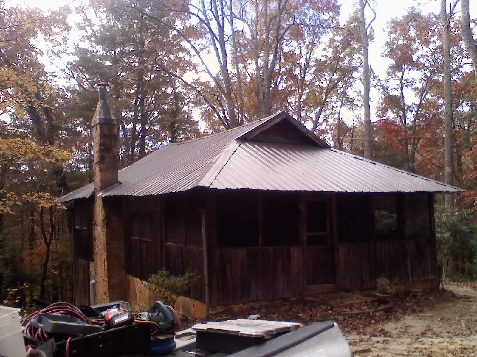 Brown metal hip roof on an old cabin with a stone chimney in Arcadia