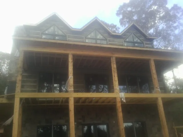 Dormers and porch framing on a large log home under construction — Roof Coating work by our crew in Arcadia